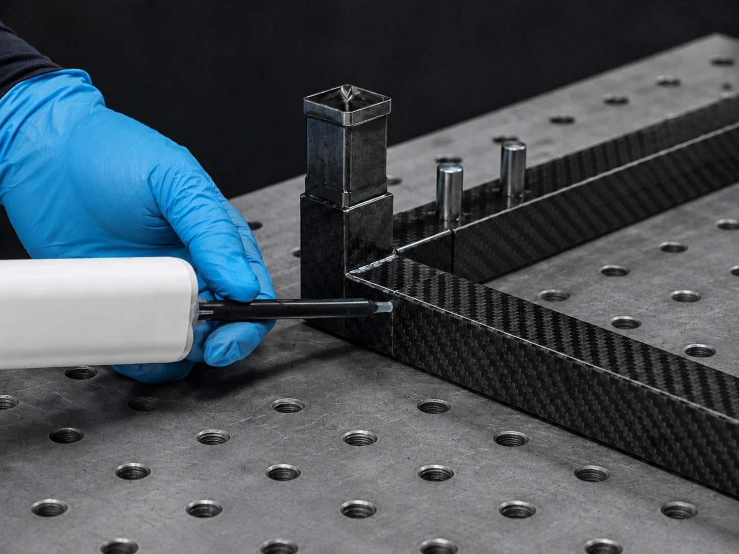 Technician applying adhesive to a carbon fiber tube joint in a fixture