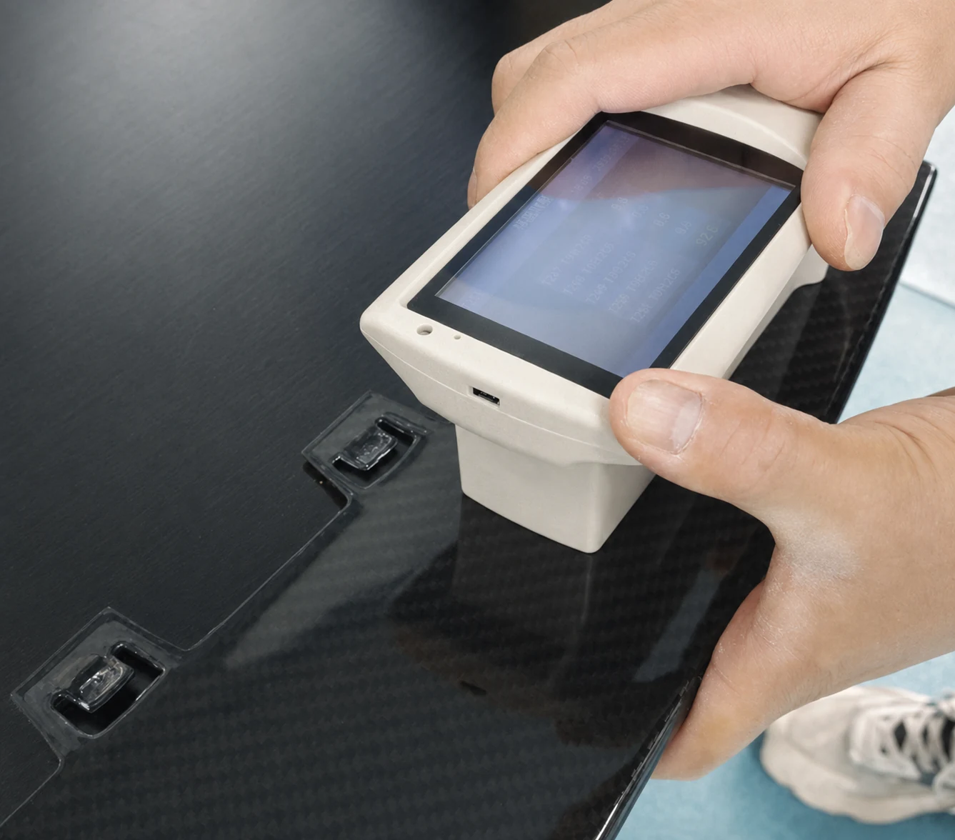Handheld instrument checking the surface of a carbon fiber component