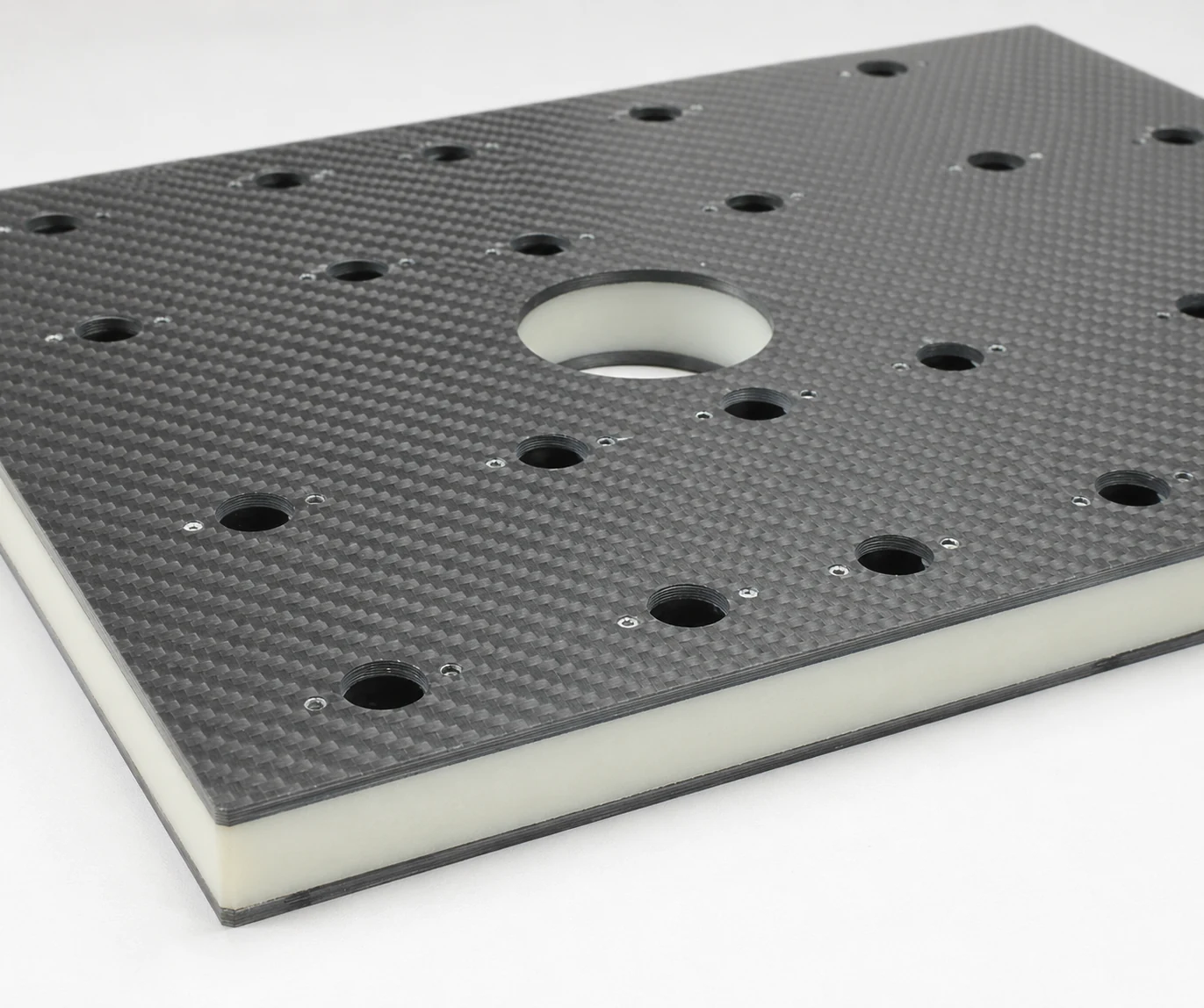 Carbon fiber sandwich panel with a light-colored core and drilled features