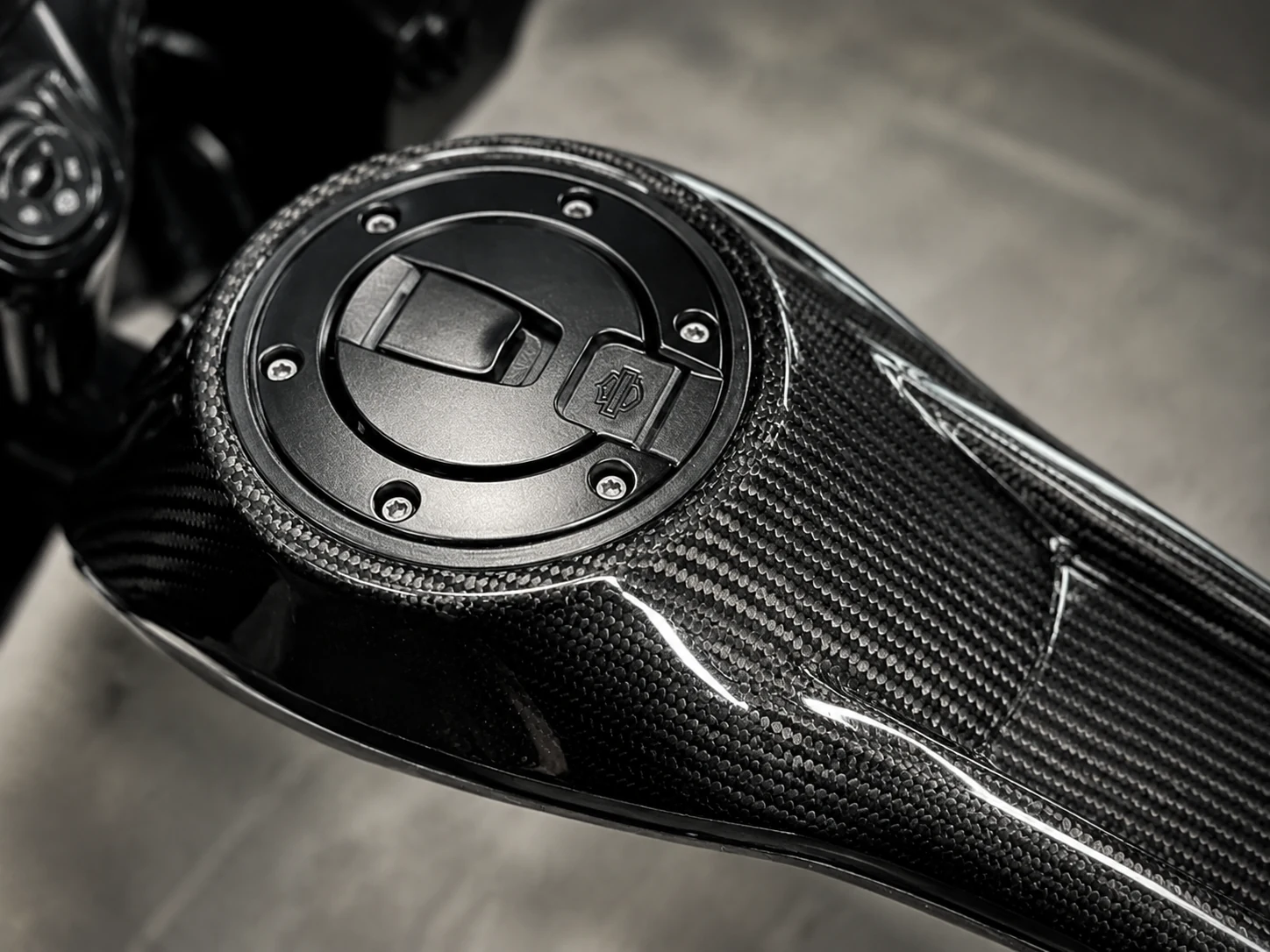Gloss carbon fiber motorcycle tank cover around a fuel cap